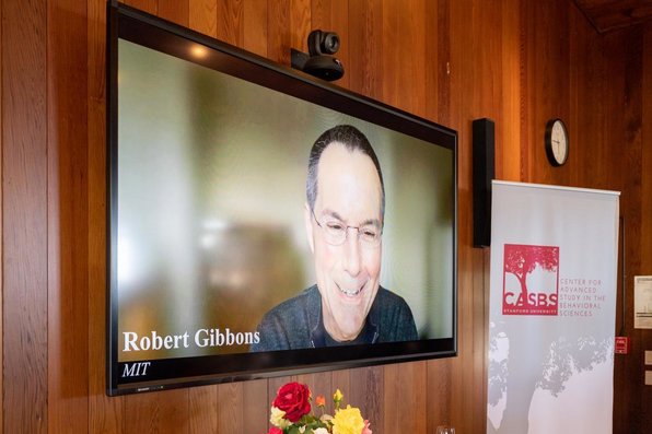 Robert Gibbons smiles from a video screen.