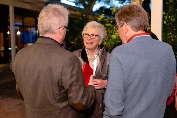 Margaret Levi smiles and talks with two other people.