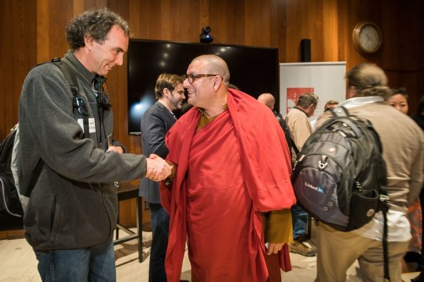 Buddhist monk shakes hands with another person.