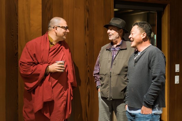 A Buddhist monk speaks with two other people.
