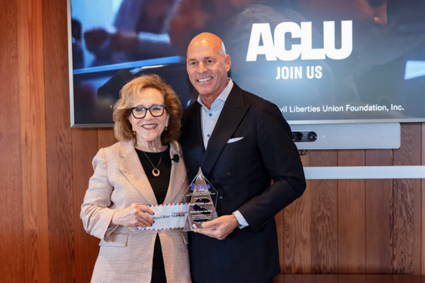 Sage CEO Blaise Simqu and Hazel Markus pose together, Simqu holding the award plaque and Markus holding an envelope containing the award check