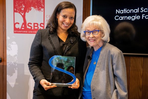 Jennifer Richeson holds the SAGE-CASBS award and she and another person smile at the camera.
