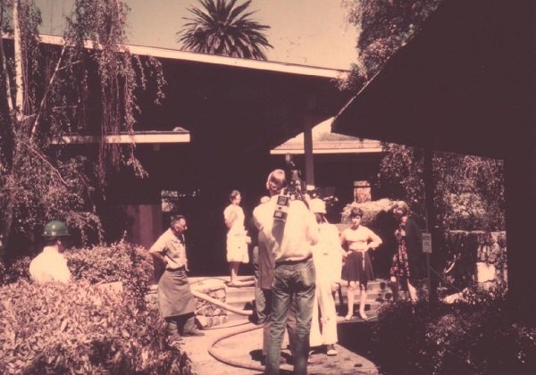 Sepia toned image of a news crew with staff and students near the scene of the arson