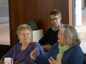 Seated woman speaking; two people listening