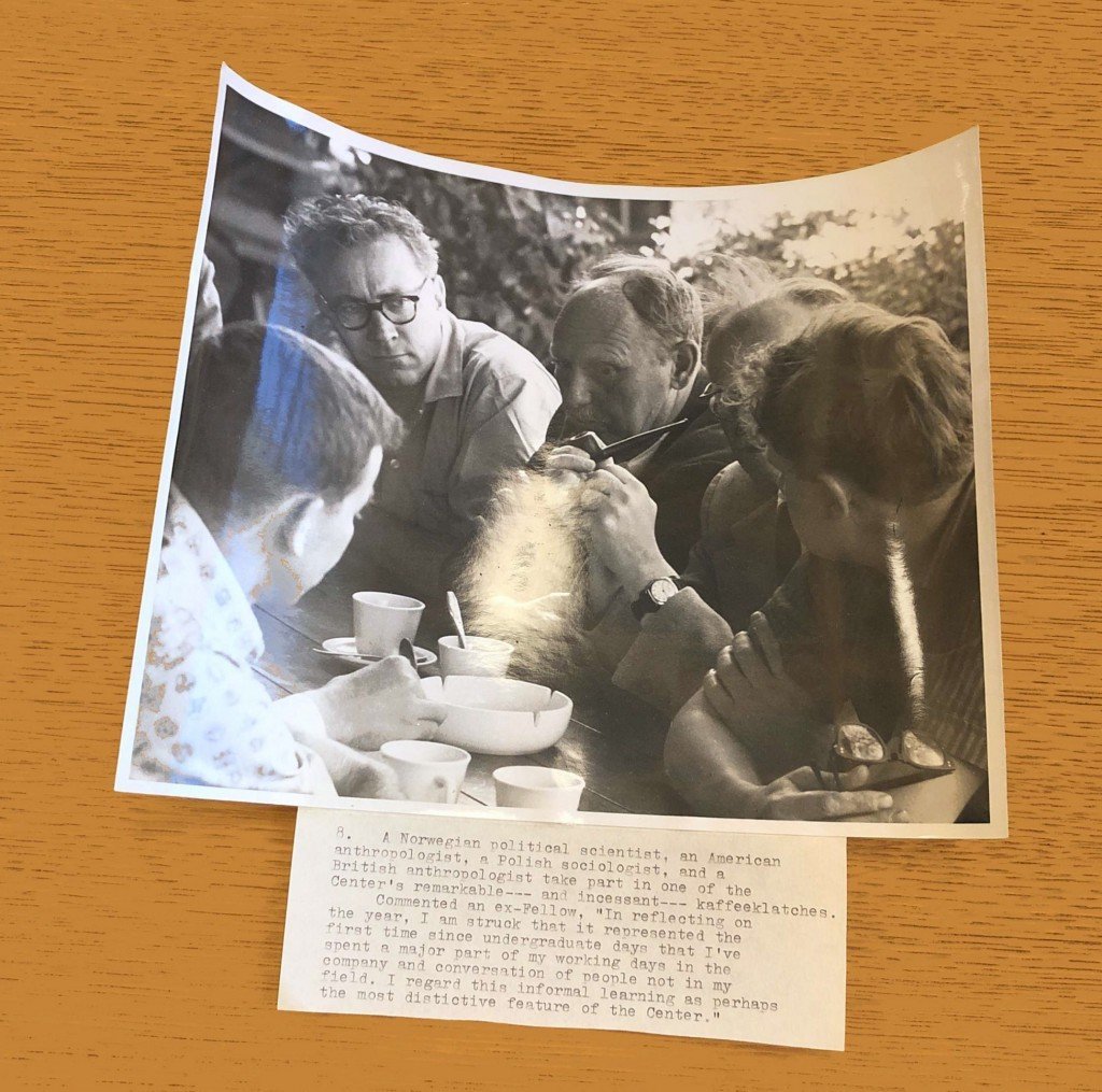 Photograph of four scholars talking over coffee