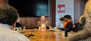 George Schultz speaks to a conference table of workshop participants