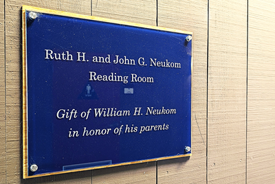Plaque on a wall that reads: "Ruth H. and John G. Neukom Reading Room | Gift of William H. Neukom in honor of his parents