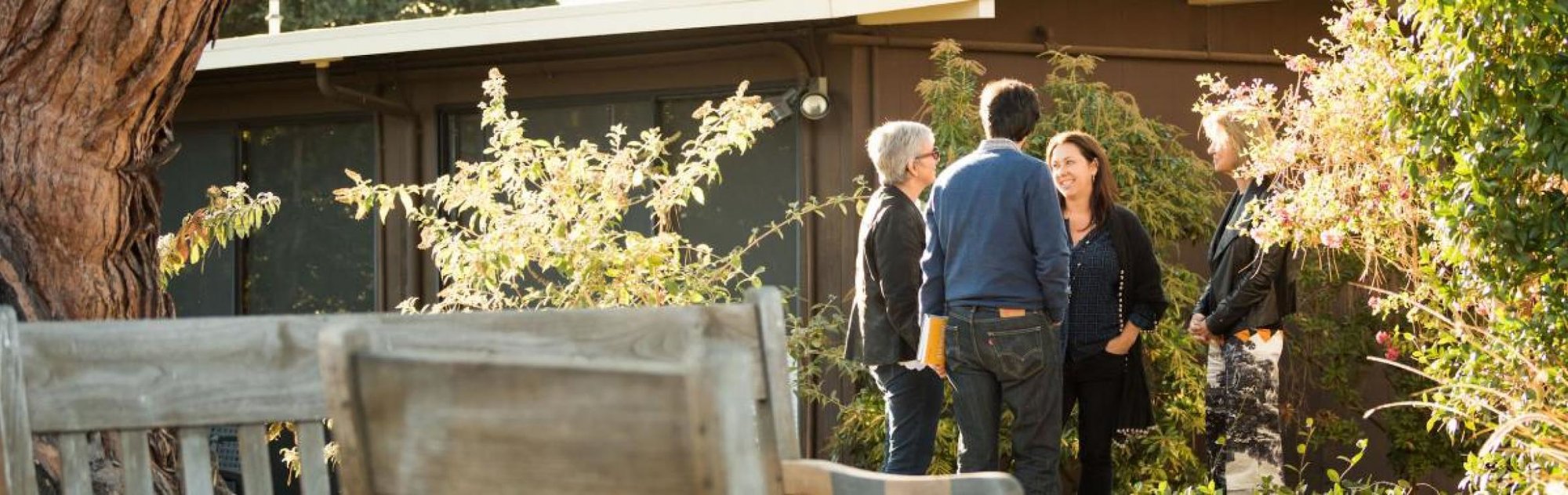 four people talking with each other outside in a courtyard